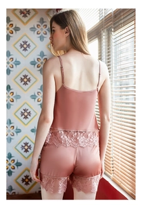 Détail d'un ensemble pyjama en satin rose poudré avec dentelle florale sur le short