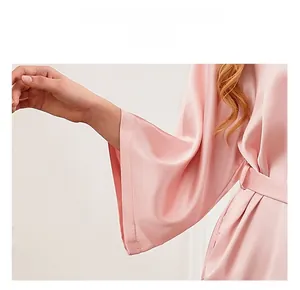 Detailed close-up showing the smooth pink satin fabric and kimono-style cuffs of the robe