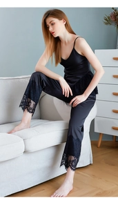 Close-up of black satin camisole set featuring intricate lace trim on the hem and pants