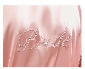 Macro shot of Bride embroidery on soft pink silk satin bridal robe with smooth texture