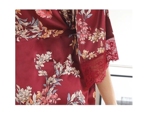 Detailed close-up of dark red satin robe with floral prints and lace trim sleeves