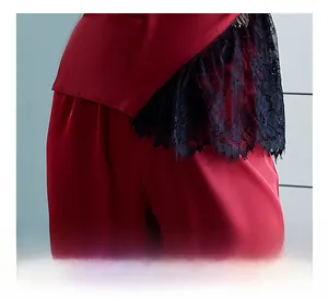 Detailed close-up of delicate black eyelash lace trim on red satin pajamas hemline