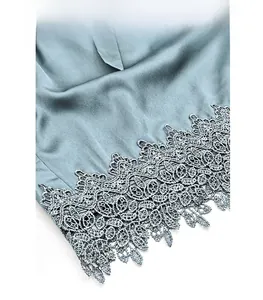 Detailed close-up of greyish-blue ice silk pajamas with elegant floral lace embroidery edge