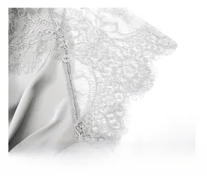 Détail en gros plan de la dentelle délicate sur la manche du vêtement en satin argenté