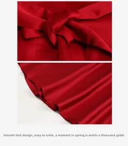 Détail d'un peignoir en soie rouge montrant la ceinture en satin et les plis du tissu