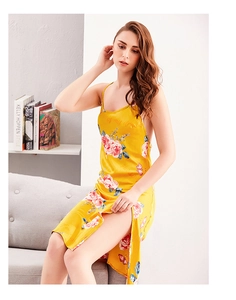 Detail of yellow satin nightgown with pink roses and high side slit on a gray sofa
