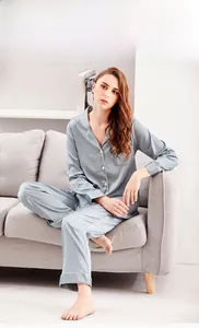 Chic women's satin pajama set featuring silk-like fabric with contrast piping on sofa