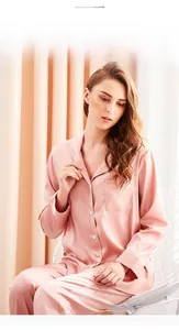 Detailed view of pink silk pajamas with white piping and breast pocket detail