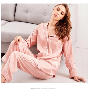Close-up of pink silk pajamas set featuring white piping detail and button-up front design