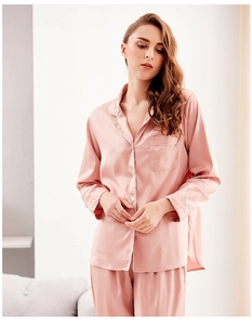 Detail of silk pajamas featuring a white piped lapel and polished buttons in pink