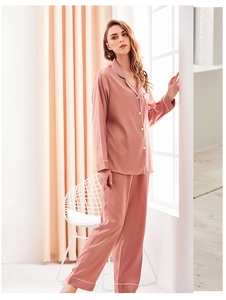 Close-up of pink satin pajama set with elegant white contrast piping and button detail