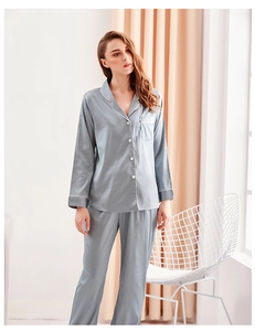 Detail of silk satin pajamas set in grey blue featuring white piping and chest pocket