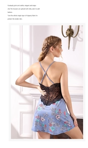 Détail des bretelles croisées et dentelle noire sur une nuisette en satin à fleurs bleues
