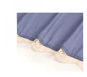 Close-up detail of smooth blue-grey silk fabric with elegant beige floral lace hemline