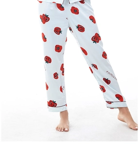 Dettaglio dei pantaloni del pigiama in raso azzurro con stampe di pomodori rossi