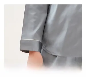 Detail of silk pajama sleeve with white piping and smooth grey satin texture