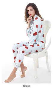 Dettaglio pigiama in raso azzurro con stampe di pomodori su sedia bianca