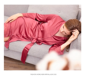 Detail of rose pink silk robe with lace cuffs and hem on a gray sofa setting