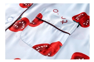 Dettaglio del pigiama in seta azzurra con stampe di pomodori e tasca profilata in rosso
