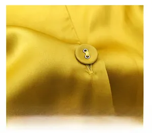 Macro shot of delicate yellow satin fabric with a matching fabric-covered button and fine stitching