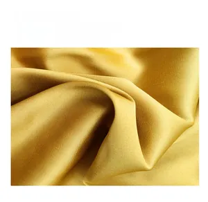 Gros plan sur le tissu satiné en soie glacée dorée à la texture lisse et fluide