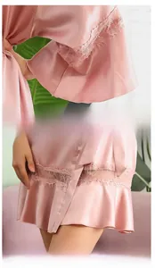 Detailed view of pink silk robe featuring intricate lace trim on sleeves and hollow hemline