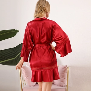 Red satin bridal robe with lace trim and waist tie shown in minimalist home setting