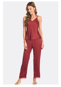 Detail of burgundy satin sleepwear set showing lace trim on the V-neck camisole and pants
