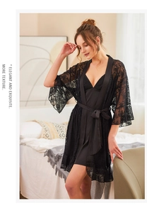 Nahaufnahme von schwarzem Spitzenmantel und Satin-Nachthemd-Set an einem Model im Schlafzimmer