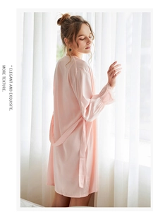 Close-up of pink satin robe with intricate lace cuffs and elegant silk-like texture