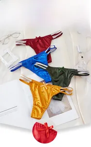 Detailed view of four colorful lace thongs with shimmering straps and bows on silk background