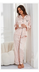 Detail view of pink leopard print silk pajamas with black piping and letter V embroidery