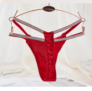 Detail view of red lace thong with glittery silver cross straps on a rose gold hanger