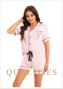 Close-up of pink modal pajamas featuring black embroidery on the pocket and piping