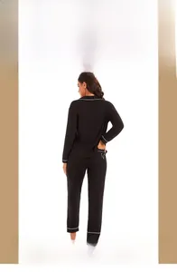 Detail of black modal pajamas featuring white piping trim and V logo on back pocket