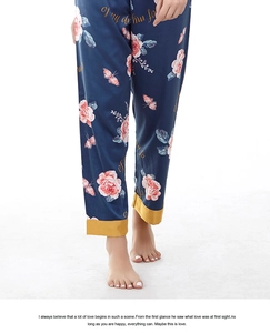 Detailed view of dark blue satin pajama pants with floral rose print and yellow contrast hem