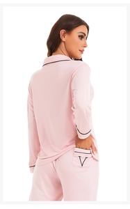 Detail view of pink modal pajama pants featuring contrast piping and a black V-shaped embroidery