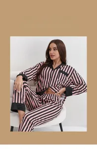 Close-up of pink and black striped pajama set with contrast collar and cuffs on a sofa
