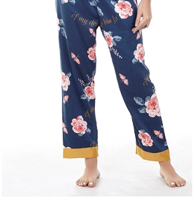 Detail of navy blue satin pajama pants with pink rose prints and golden trim hem