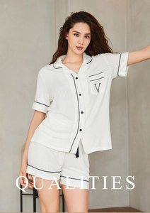 Détail d'un pyjama en modal blanc à rayures verticales, liseré noir et broderie en V