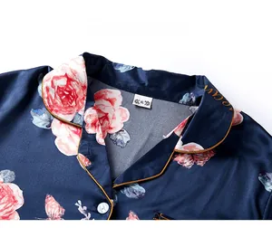 Macro shot of navy satin pajama collar with pink rose print and gold piping detail