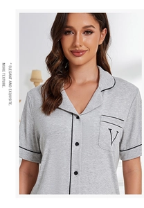 Detail of light grey modal cotton pajama top with black piping and embroidered letter V