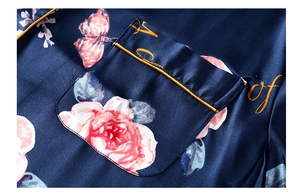 Close-up of dark blue satin fabric with pink roses and gold piping detail on pocket
