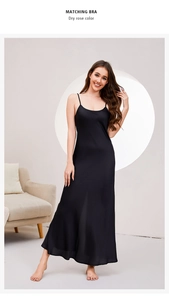 Detail view of long black satin slip nightdress with matching bra and sleek silk texture