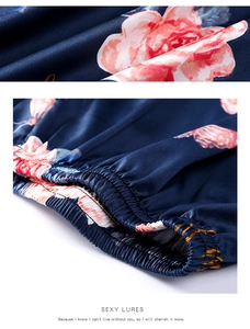 Close-up of dark blue silk satin pajamas with pink floral patterns and elastic cuffs