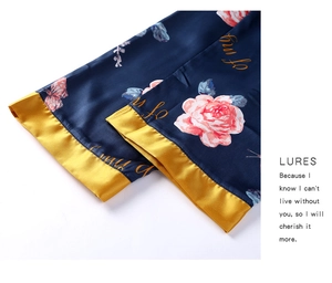 Detail of dark blue satin pajama pants with floral print and gold contrast hem cuffs