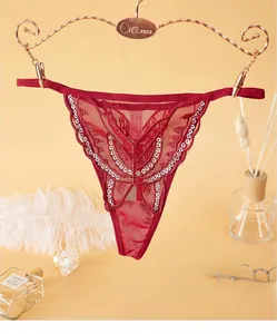 Détail d'un string en dentelle rouge avec papillon à paillettes et maille fine transparente