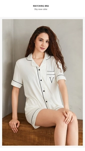 Détail d'un pyjama en modal blanc avec liseré noir et broderie V sur la poche