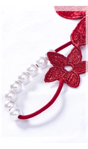 Macro shot of red floral embroidery details and white pearls on sheer lace lingerie