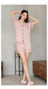 Détail de pyjama rose en modal avec texture rayée, liseré noir et broderie sur la poche en V